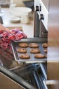 Cropped image of woman's hand removing cookie tray from oven in kitchen