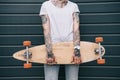 cropped image of woman with tattoos holding skateboard against black