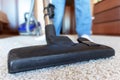 Cropped image of a woman using a vacuum cleaner brush while cleaning a beige carpet Royalty Free Stock Photo