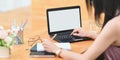 Cropped image woman is using a white blank screen computer laptop at the wooden working desk Royalty Free Stock Photo