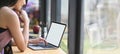 Cropped image woman is using a white blank screen computer laptop at the wooden working desk Royalty Free Stock Photo