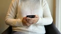 Cropped image of a woman using her phone while sitting at a chair in a coffee shop Royalty Free Stock Photo