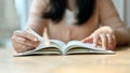 Cropped image, Young Asian female college student reading a book in the library or coffee shop Royalty Free Stock Photo