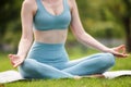 Cropped image of young calm woman in sportswear sitting in lotus position outdoors in park Royalty Free Stock Photo