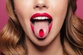 Cropped image of young lady with red lips holding pill in mouth Royalty Free Stock Photo