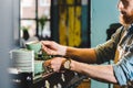 cropped image of young male barista in apron taking mugs in coffee