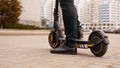 Cropped image of young man riding in the street on electric kick scooter Royalty Free Stock Photo