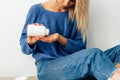 Cropped image of young woman pours the pills out of the bottle. Young blonde female wearing blue knitted sweater pouring some Royalty Free Stock Photo