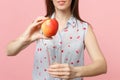 Cropped image of young woman in summer clothes holding fresh ripe red apple fruit, glass cup isolated on pink pastel Royalty Free Stock Photo