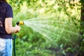 Cropped image of young woman watering flowers and plants in garden with hose in sunny blooming backyard Royalty Free Stock Photo