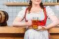 cropped imageo of oktoberfest bartender in traditional bavarian dress holding mug of light beer Royalty Free Stock Photo