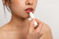Cropped of korean lady using lipbalm, taking care of her beautiful lips, putting hygienic lipstick, white background Royalty Free Stock Photo