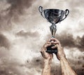 Cropped male arms with winner cup. Royalty Free Stock Photo