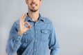 Cropped Man in studio in denim shirt doing okay sign with hand copy-space