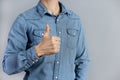 Cropped Man in studio in denim shirt showing thumb up with hand copy-space
