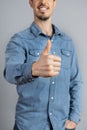 Cropped Man in studio in denim shirt showing thumb up with hand copy-space