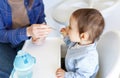 cropped mother feed little toddler baby boy with baby food, from plastic spoon in high chair front view. Motherhood Royalty Free Stock Photo