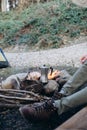 Cropped outdoor image of young man explorer sitting near to bonfire preparing hot beverage in mountains. Concept adventure