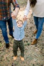 Cropped outdoor shot of happy family in stylish casual clothes, playing and having fun in autumn pine forest, holding Royalty Free Stock Photo