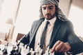 Cropped photo of Arab playing chess at table.