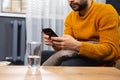 Cropped photo of a beard adult man, dependent of virtual world. Online psychotherapy session, a glass of water on the table. A Royalty Free Stock Photo