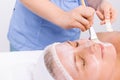 Cropped photo of a beautician applying a moisturizing face mask with a cosmetic brush to a senior woman a headband