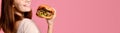 Close up portrait of a hungry young woman eating burger isolated over pink background