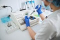 Medical lab technician drawing off liquid from a reagent bottle