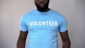 Cropped photo of black male volunteer in blue t-shirt, helping homeless people