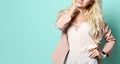 Girl in beige jacket and white overall. Smiling, folded her hands, posing standing against green studio background. Close-up