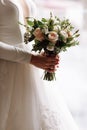 Cropped photo of bride in white wedding luxury dress with bouquet of flowers roses near the window in hotel room. wedding day Royalty Free Stock Photo