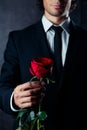 Cropped photo of business man holding a red rose in his hand. He