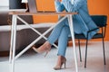 Cropped photo. Businesswoman indoors in room with orange colored wall and wooden table