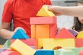 Cropped photo of children sitting at table in kitchen, building tower house of construction blocks geometric figures. Royalty Free Stock Photo