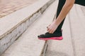 Cropped photo close up of female hands tying shoelaces on woman black and pink sneakers on training on stairs outdoors Royalty Free Stock Photo