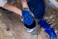 Cropped photo of folded hands of woman stained with blue paint over bucket on transparent film covered with splashes.