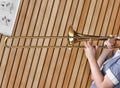 Cropped photo of girl playing trombone in music class