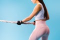 Cropped photo of a girl with pumped up buttocks pulling a rope on a blue background.