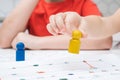 Cropped photo of group of children playing tabletop game, holding yellow figure over white board, thinking, counting. Royalty Free Stock Photo