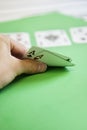 Cropped shot of hand holding aces of hearts and clubs on green surface