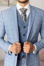 Cropped photo of man groom wearing blue stylish checkered suit, vest, white shirt, grey tie, holding jacket with hands. Royalty Free Stock Photo