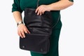 Cropped photo of married, young large woman searching in her handbag isolated on gray background. Displeased woman