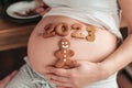 Cropped photo of pregnant woman holding number 2023 of ginger cookies on belly.