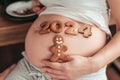 Baby born in 2024. Cropped photo of pregnant woman holding number 2024 of ginger cookies on belly.