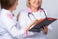 Cropped photo of senior doctor with stethoscope near young medical resident in white coat, showing medical information, diagnosis Royalty Free Stock Photo