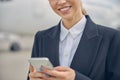Pleased airport female employee holding a smartphone Royalty Free Stock Photo