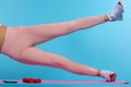 Cropped photo of sportwoman, female legs, practicing fitness doing side plank pose on blue background