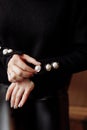 Cropped photo of a stylish woman in black outfit with pearls details. ashion concept