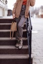 Cropped photo of a stylish young woman holding beige handbag on the stairs Royalty Free Stock Photo