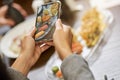 Skillful person taking photo of sushi plate on a smartphone